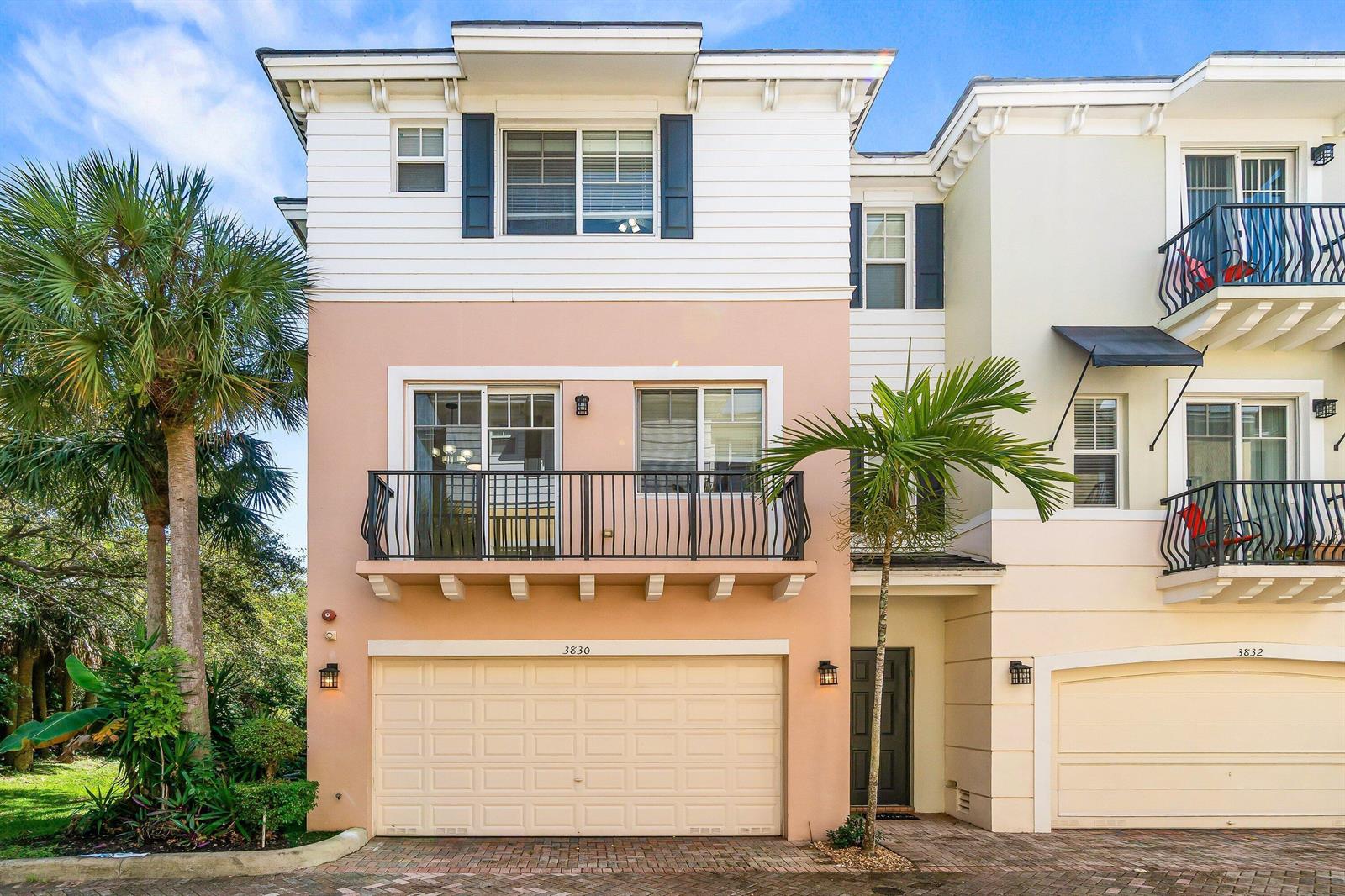 A three-story townhouse exterior features a peach-colored facade, a two-car garage, and a balcony — 3830 NW 5th Terrace, Boca Raton FL 33431, BOCA RATON, FL