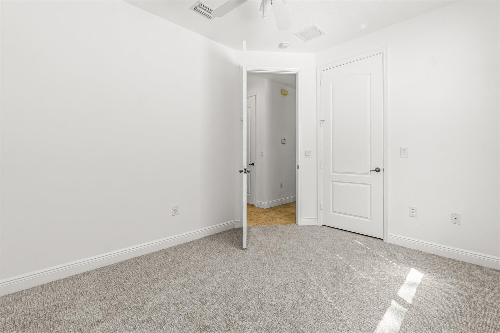 An empty room with white walls, gray carpet, and two white interior doors — 3830 NW 5th Terrace, Boca Raton FL 33431, BOCA RATON, FL