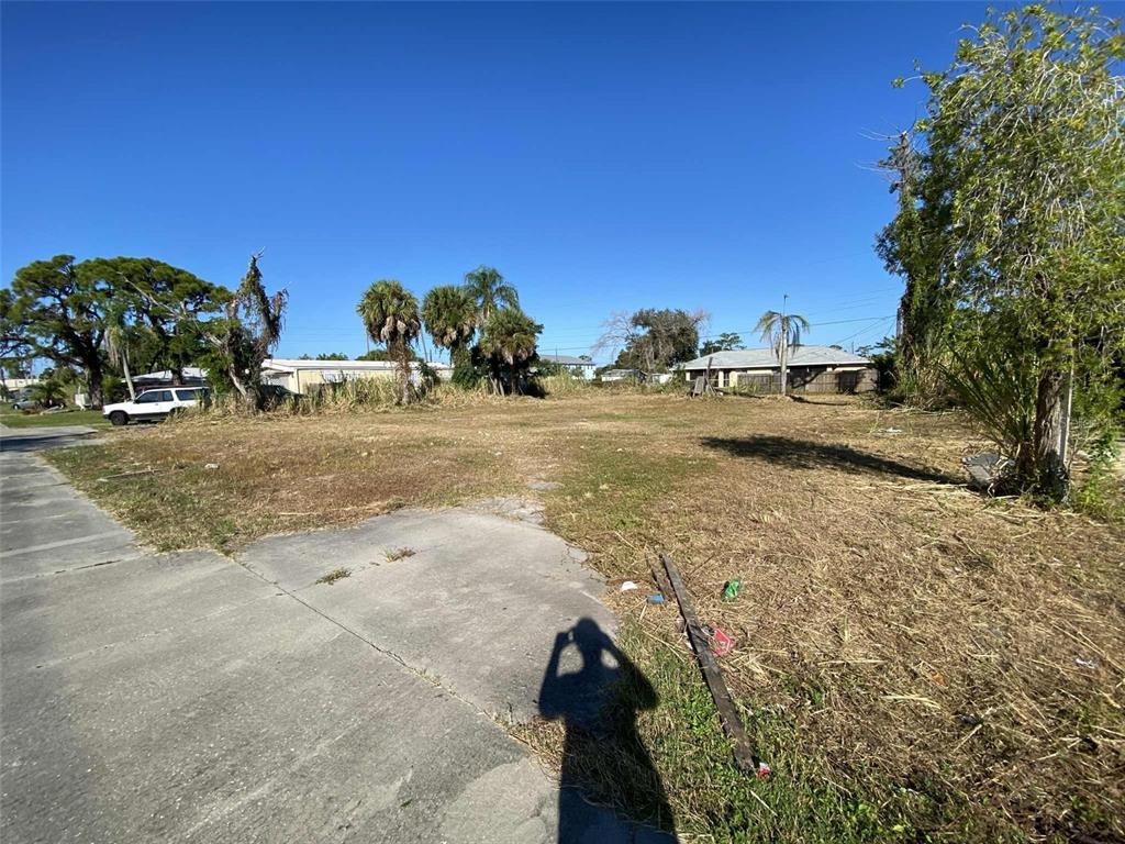 A vacant, grassy lot features a concrete driveway apron under a clear blue sky — 7439 SAN CASA DRIVE, ENGLEWOOD, FL