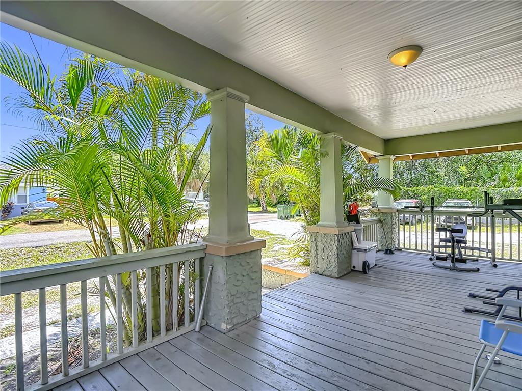 A covered wooden porch features square columns with stone bases and a metal railing — 2020 DAVIS STREET, TAMPA, FL