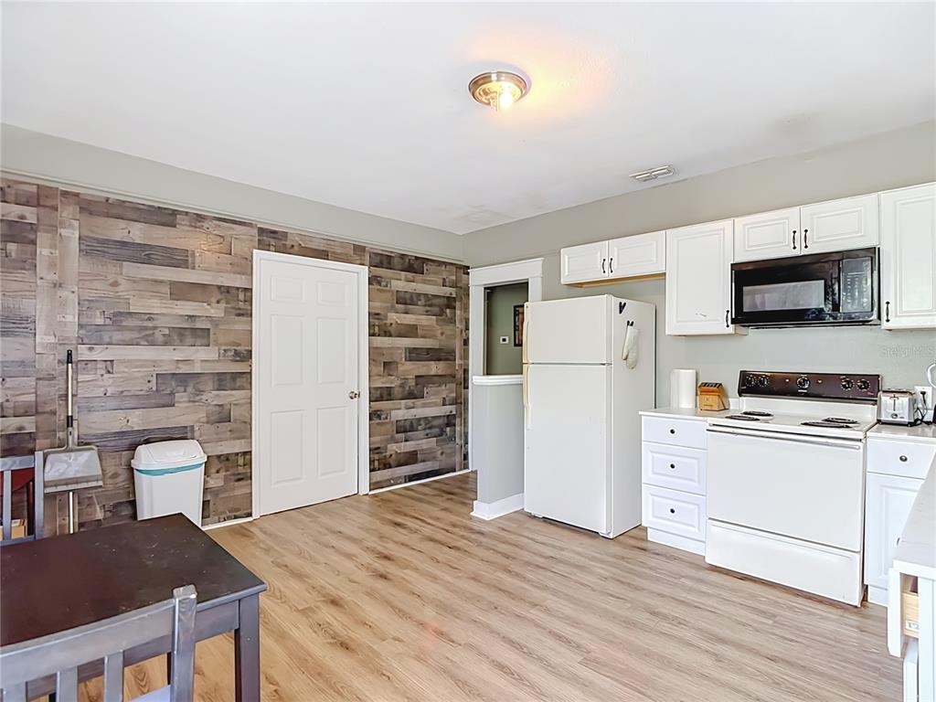 A kitchen and dining area features wood-plank accent walls, white cabinetry, and light wood flooring — 2020 DAVIS STREET, TAMPA, FL