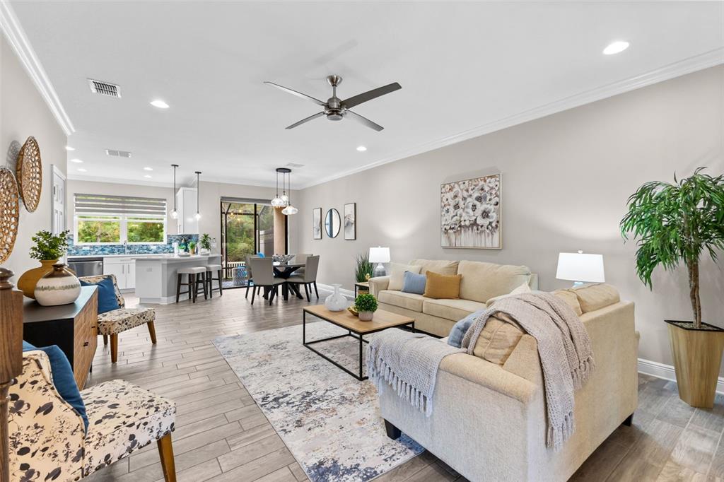 An open-concept living area features a kitchen, dining space, and living room with tile flooring — 11458 CROWNED SPARROW LANE, TAMPA, FL