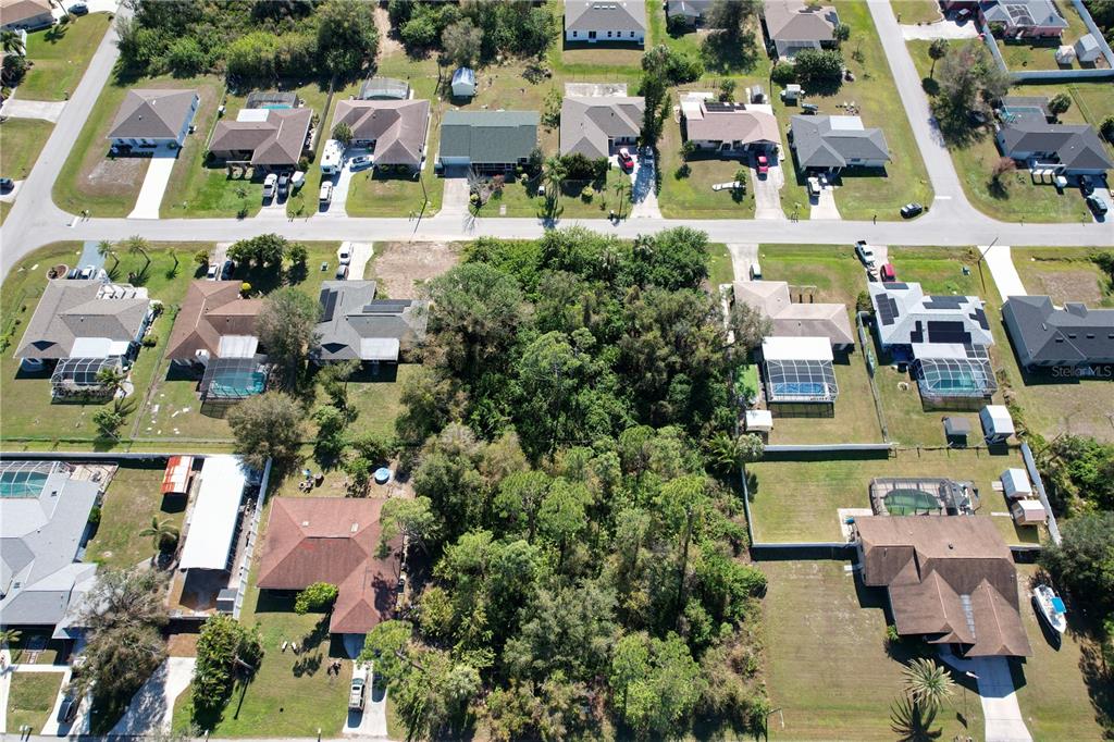 Aerial view of a wooded residential lot surrounded by houses with swimming pools — 16150 ARCARO AVENUE, PORT CHARLOTTE, FL