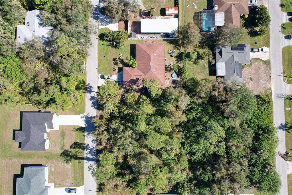 An aerial view shows a residential property with a house, surrounding trees, and nearby roads — 16150 ARCARO AVENUE, PORT CHARLOTTE, FL