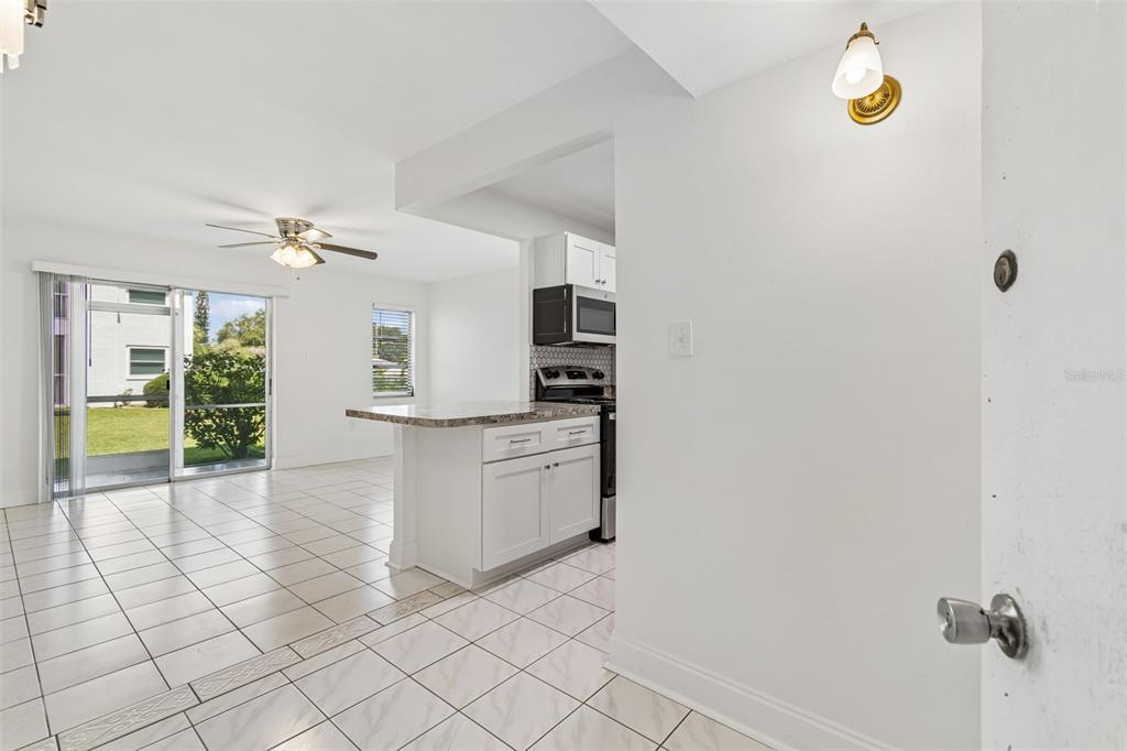 A view from an entryway into a kitchen with white cabinets and a tiled floor — 237 S MCMULLEN BOOTH ROAD UNIT 51, CLEARWATER, FL