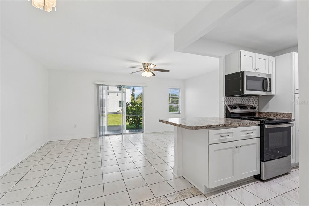 A kitchen with white cabinets and a breakfast bar opens into a tiled living area — 237 S MCMULLEN BOOTH ROAD UNIT 51, CLEARWATER, FL