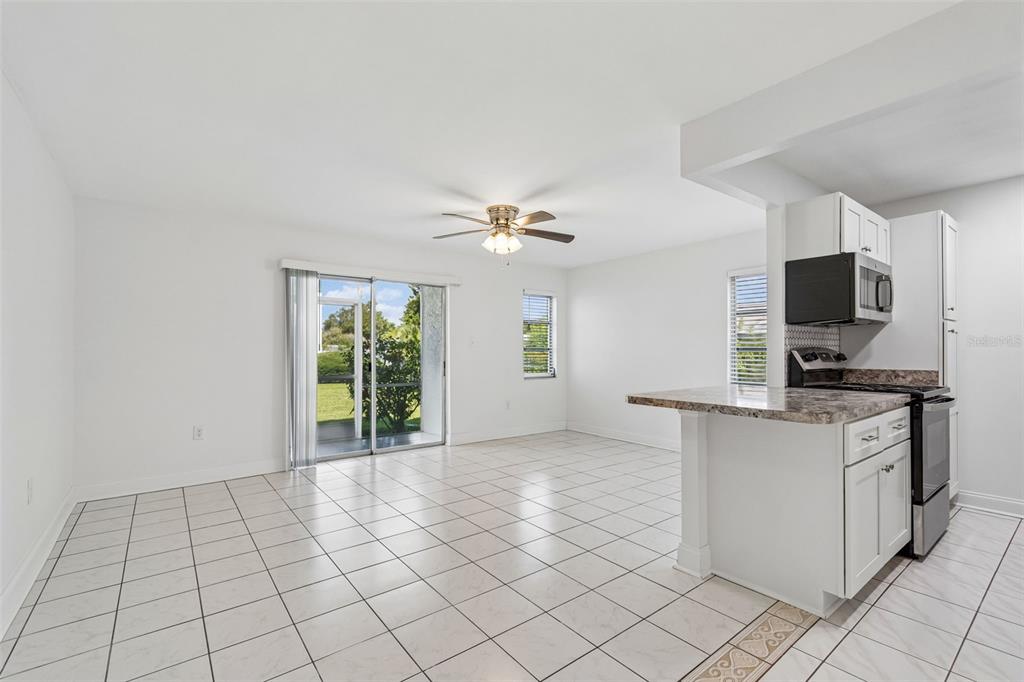 A bright, tiled living area features a ceiling fan and sliding glass doors to outside — 237 S MCMULLEN BOOTH ROAD UNIT 51, CLEARWATER, FL