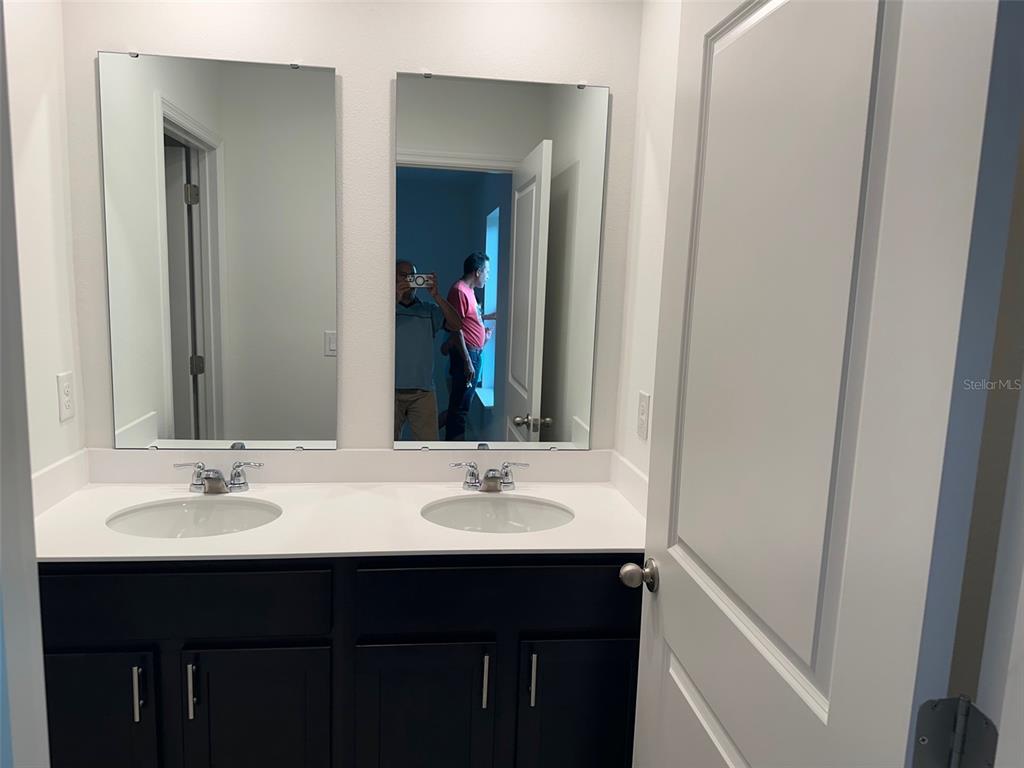 A bathroom features a dark double vanity with white countertops and two frameless wall mirrors — 737 MAPLE OAK DRIVE, DELAND, FL