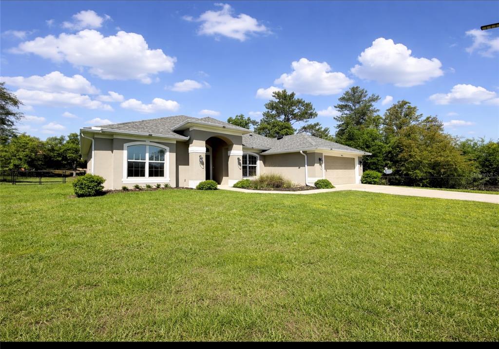 A single-story tan stucco house with a gray shingled roof and a two-car garage — 9832 SW 46TH COURT, OCALA, FL