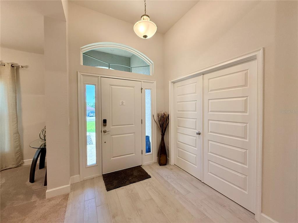 An entryway features a white front door, a double-door closet, and light-colored wood-look flooring — 9832 SW 46TH COURT, OCALA, FL