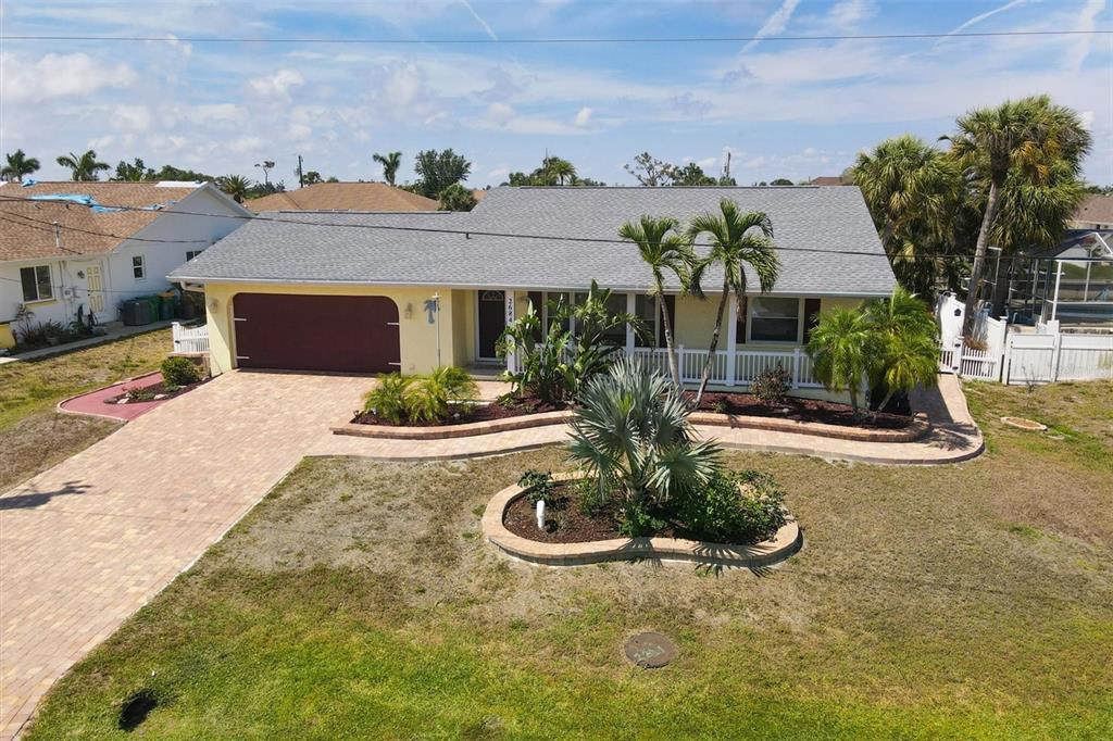 An aerial view shows a single-story yellow house with a gray roof and paved driveway — 2684 TITANIA ROAD, ENGLEWOOD, FL