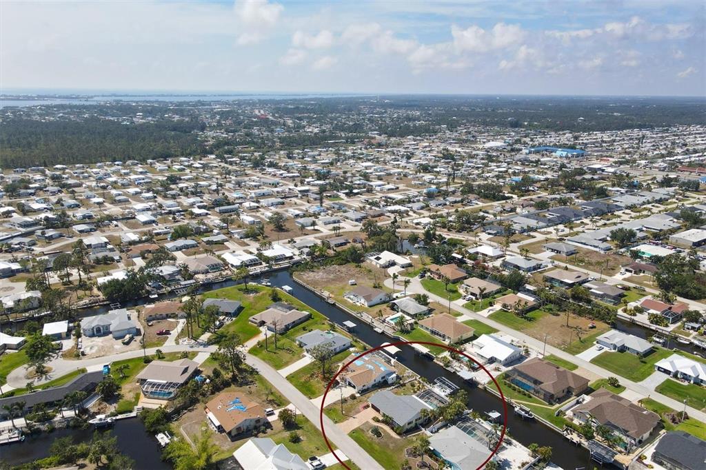 An aerial view shows a residential neighborhood with houses situated along a canal — 2684 TITANIA ROAD, ENGLEWOOD, FL