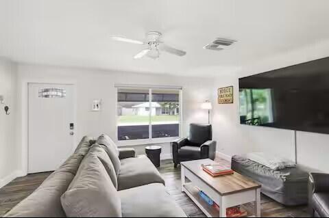 A living room features a gray sectional sofa, a coffee table, and a wall-mounted television — 1519 Treemont Avenue, Jupiter FL 33469, JUPITER, FL