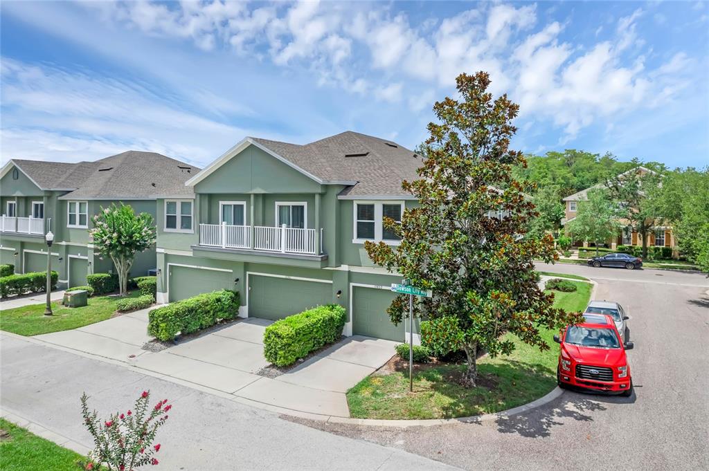 A green two-story townhouse with a multi-car garage and a large tree in front — 10802 ECLIPSE LILY WAY UNIT 50A, ORLANDO, FL