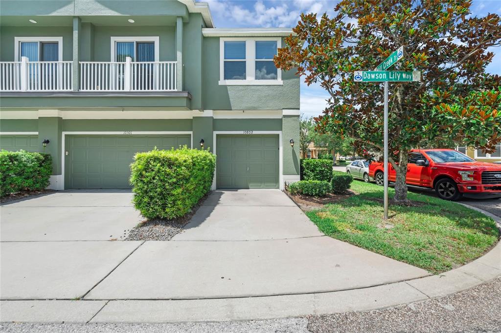 An exterior view of a green two-story townhouse with a driveway and attached garage — 10802 ECLIPSE LILY WAY UNIT 50A, ORLANDO, FL