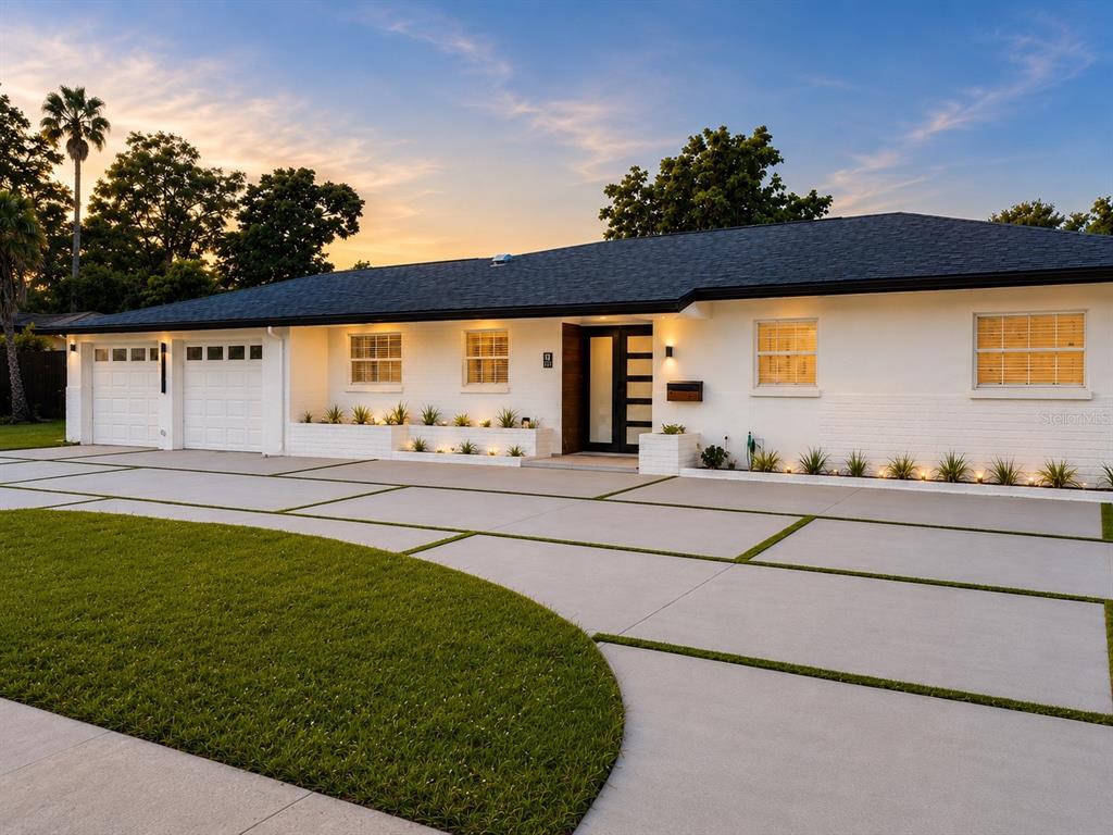 A single-story white house with a modern front door and a large concrete driveway — 1712 INDIAN ROCKS ROAD, BELLEAIR, FL