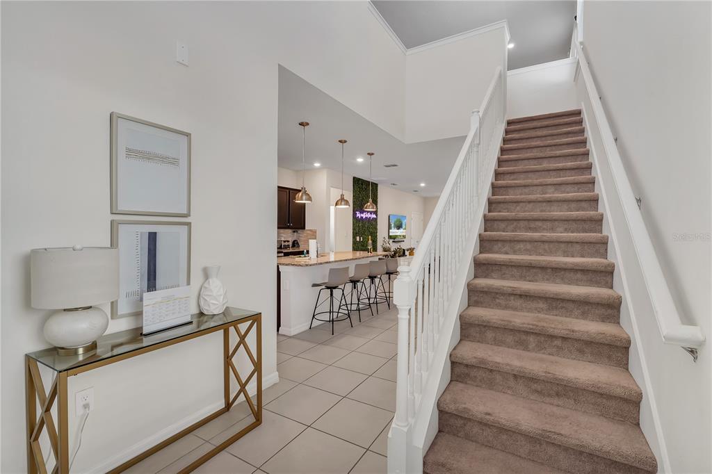 A foyer with a console table and staircase leads to an open kitchen with bar seating — 2201 LELANI CIRCLE, DAVENPORT, FL