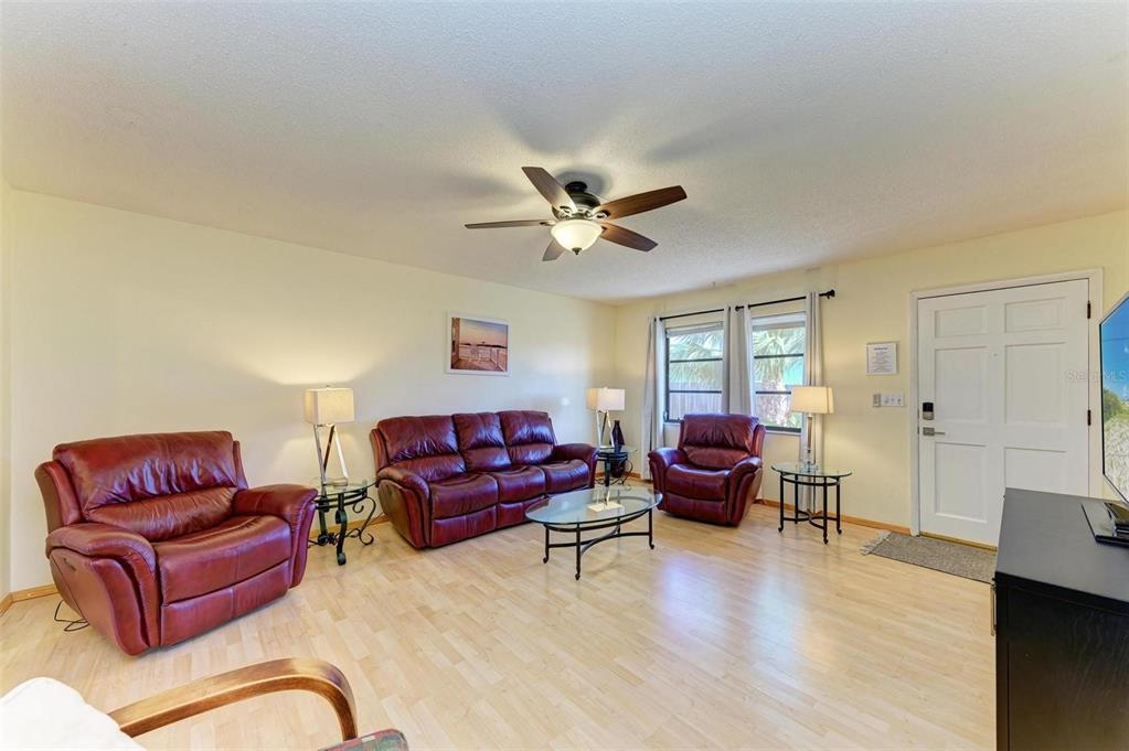 A living room features light wood flooring, a ceiling fan, and three burgundy leather chairs — 401 SHORE ROAD, NOKOMIS, FL