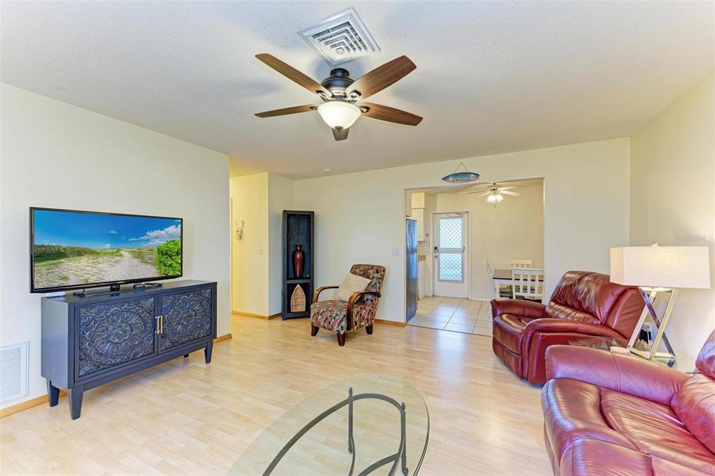 A living room features light wood flooring, a ceiling fan, and red leather furniture — 401 SHORE ROAD, NOKOMIS, FL