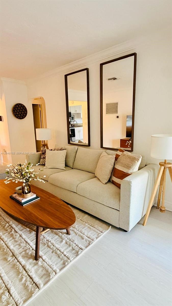 A living room features a light-colored sofa, a wooden coffee table, and two wall mirrors — HOLLYWOOD, FL
