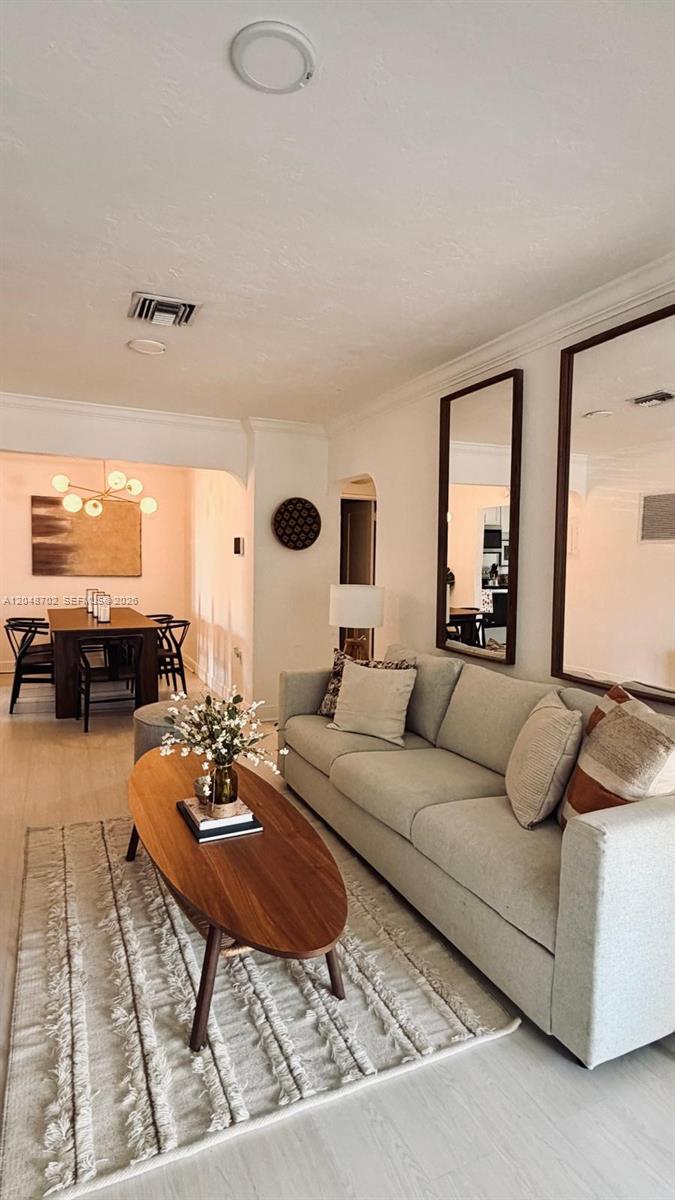 A living room with a light-colored sofa, oval wood coffee table, and adjacent dining area — HOLLYWOOD, FL