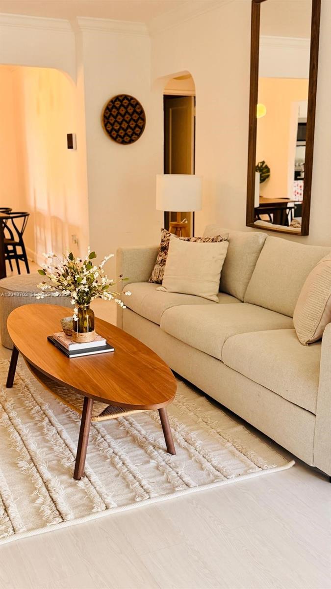 A living room features a beige sofa, an oval wooden coffee table, and a wall mirror — HOLLYWOOD, FL