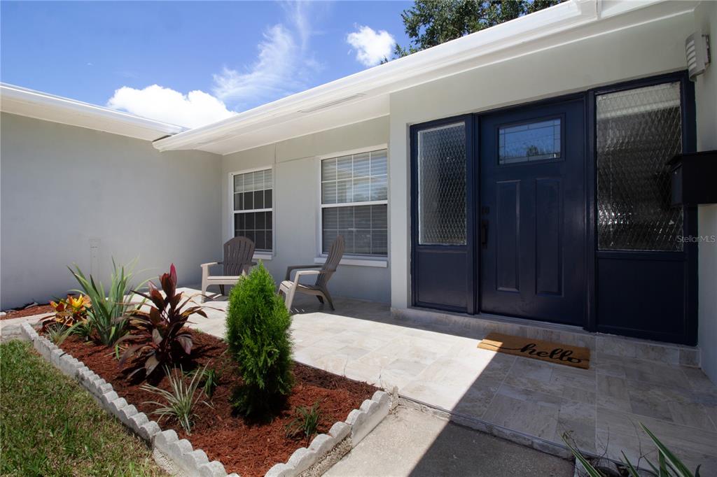 A front porch with a dark blue door, two chairs, and a landscaped garden bed — 5919 33RD AVENUE N, ST PETERSBURG, FL
