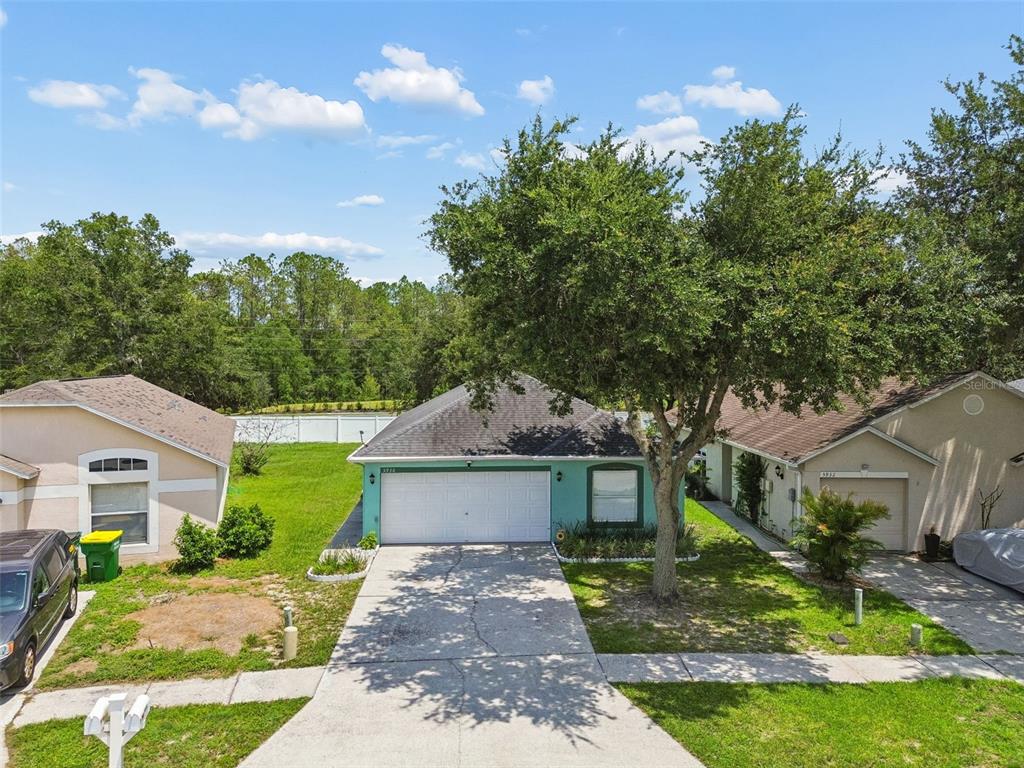 An aerial view shows a teal single-story house with a white garage and a driveway — 5936 LAKE FRONT DRIVE, WESLEY CHAPEL, FL