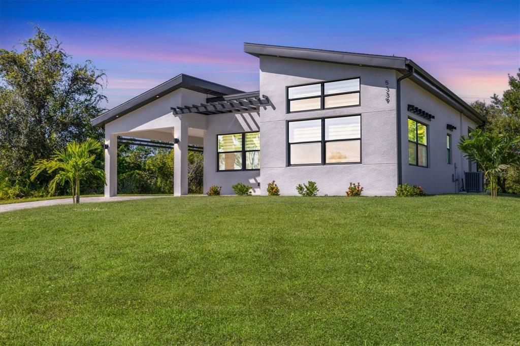 A modern, single-story house with a slanted roof, white stucco exterior, and a covered entryway — 5339 GULFPORT TERRACE, PORT CHARLOTTE, FL