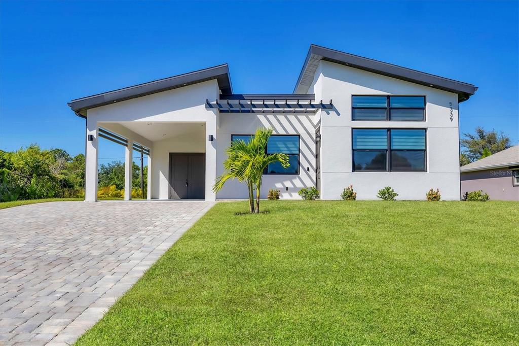 A modern white house with a slanted roof, a paved driveway, and a covered entryway — 5339 GULFPORT TERRACE, PORT CHARLOTTE, FL