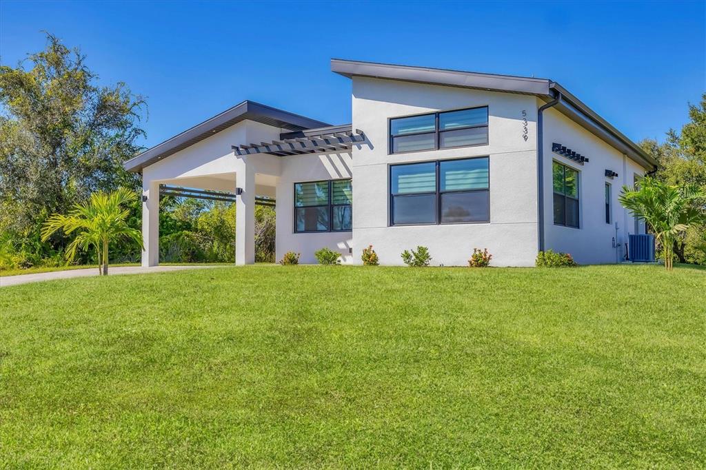 A modern white house with a flat roof and a pergola over the entryway — 5339 GULFPORT TERRACE, PORT CHARLOTTE, FL