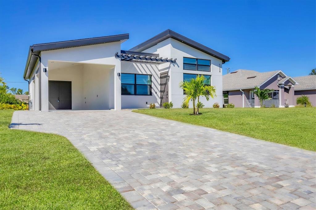 A modern white house with a paved driveway, a carport, and a pergola entrance — 5339 GULFPORT TERRACE, PORT CHARLOTTE, FL
