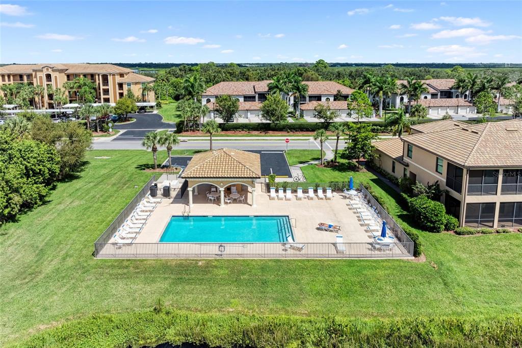 An aerial view of a rectangular swimming pool with a covered patio and lounge chairs — 6515 GRAND ESTUARY TRAIL UNIT 402, BRADENTON, FL