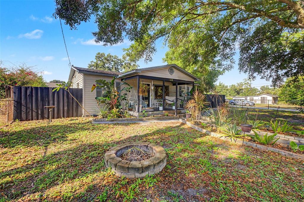 A single-story house with a covered front porch and a stone fire pit in front — 1318 W RAMBLA STREET, TAMPA, FL