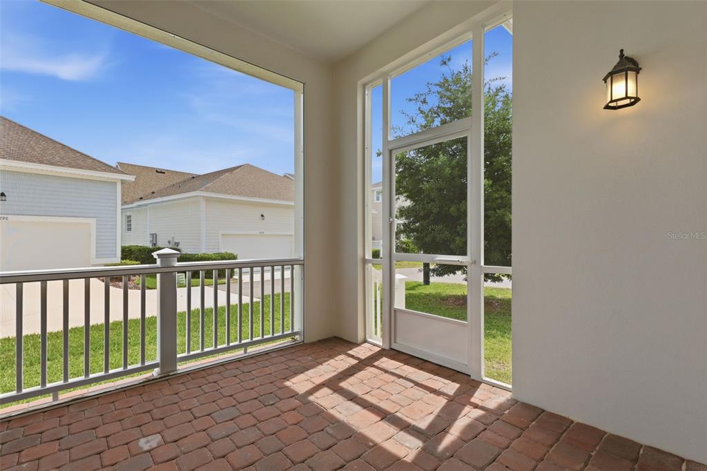 A screened-in porch features brick flooring, a white railing, and a door leading outside — 7410 BARRIER COVE WAY, KISSIMMEE, FL