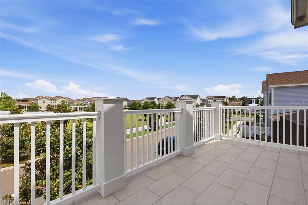 A second-story balcony features white railings, light-colored tile flooring, and views of a suburban neighborhood — 7410 BARRIER COVE WAY, KISSIMMEE, FL