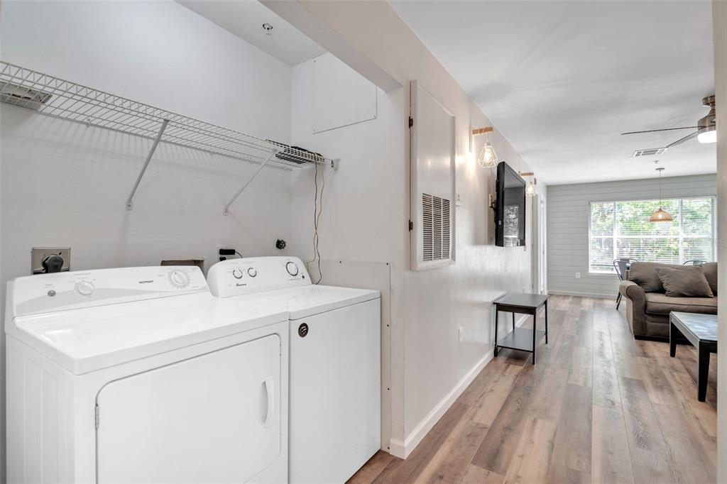 A laundry area with a washer and dryer sits adjacent to a living room — 3800 SW 20TH AVENUE UNIT 112, GAINESVILLE, FL