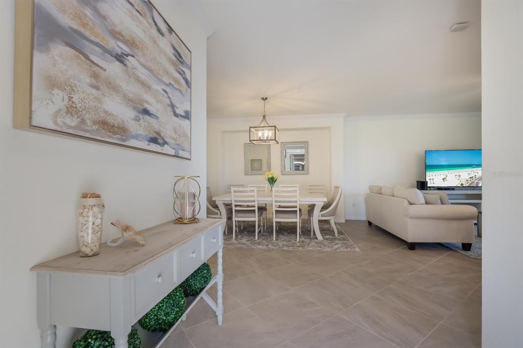 A view from a hallway into a dining room and living area with tile floors — 18017 GAWTHROP DRIVE UNIT 104, BRADENTON, FL