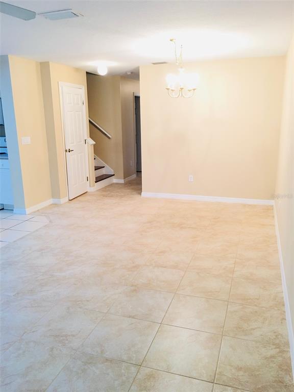 An interior view shows a dining area with beige walls, tile flooring, and a chandelier — 2764 CLUB CORTILE CIRCLE, KISSIMMEE, FL