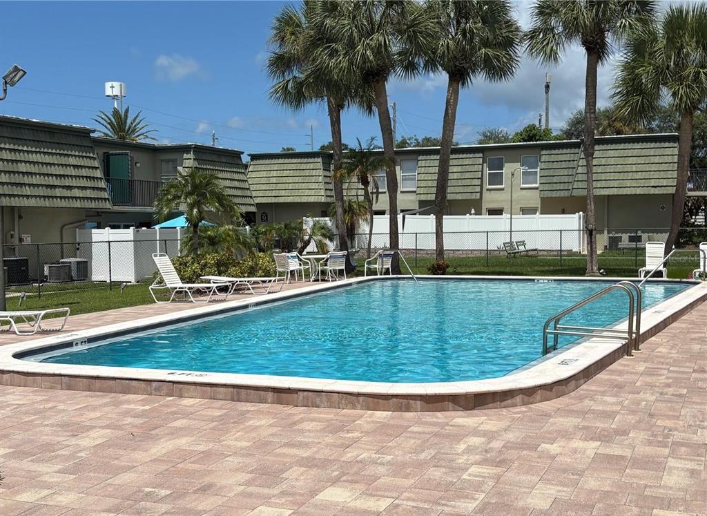 A rectangular swimming pool sits on a paved patio in front of two-story apartment buildings — 1799 N HIGHLAND AVENUE UNIT 22, CLEARWATER, FL