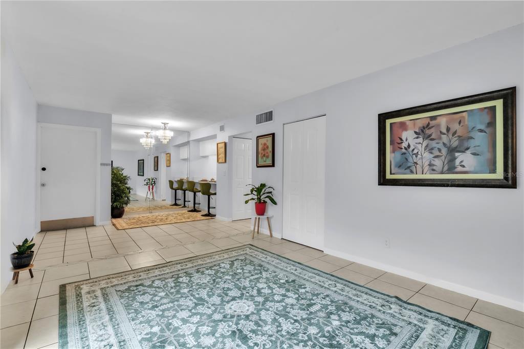 A tiled living area features a large area rug, a mirrored wall, and wall art — 1799 N HIGHLAND AVENUE UNIT 22, CLEARWATER, FL