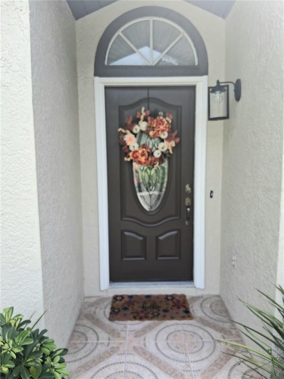 A brown front door with a decorative glass insert and wreath sits under an arched transom — 1239 LAKE PIEDMONT CIRCLE, APOPKA, FL