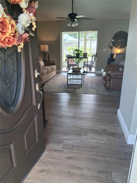 An entryway opens into a living room with wood-look flooring, a ceiling fan, and patio access — 1239 LAKE PIEDMONT CIRCLE, APOPKA, FL