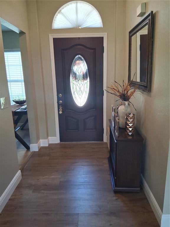An entryway features a dark wood front door with a glass oval insert and wood flooring — 1239 LAKE PIEDMONT CIRCLE, APOPKA, FL