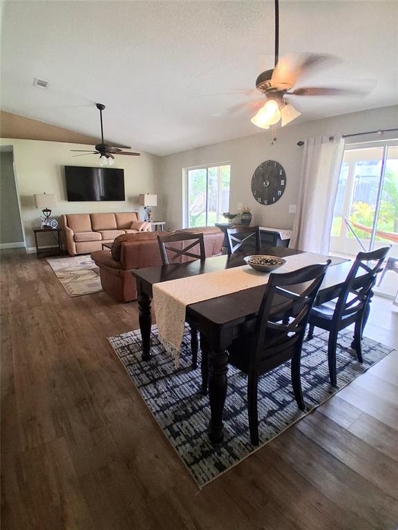 An open-concept living and dining area features wood-look flooring, a ceiling fan, and sliding doors — 1239 LAKE PIEDMONT CIRCLE, APOPKA, FL