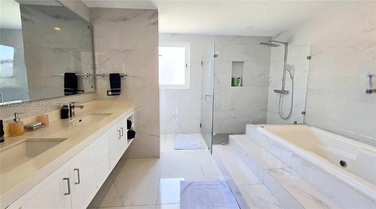A modern bathroom features a double vanity, a glass-enclosed shower, and a raised soaking tub — 0 la palmass, FL