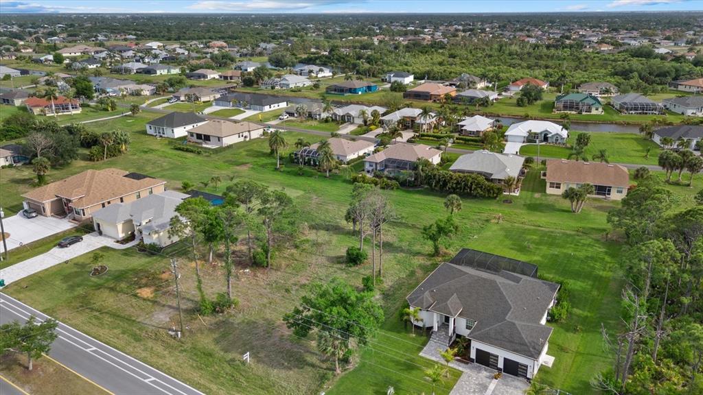 An aerial view shows a residential neighborhood with single-family homes and a vacant lot — 170 ROTONDA BOULEVARD E, ROTONDA WEST, FL