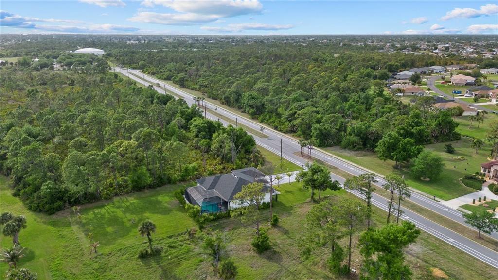 An aerial view shows a single-family house with a pool next to a paved road — 170 ROTONDA BOULEVARD E, ROTONDA WEST, FL