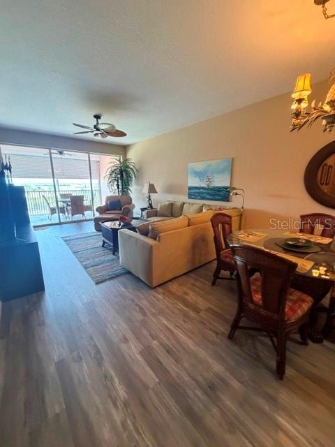 This living and dining area features wood-look flooring, a beige sofa, and a balcony view — 13413 GASPARILLA ROAD UNIT 304, PLACIDA, FL