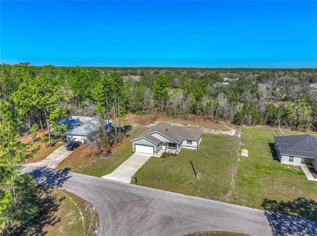 An aerial view shows a single-story house with a garage and driveway in a wooded area — 15062 SW 63RD COURT ROAD, OCALA, FL